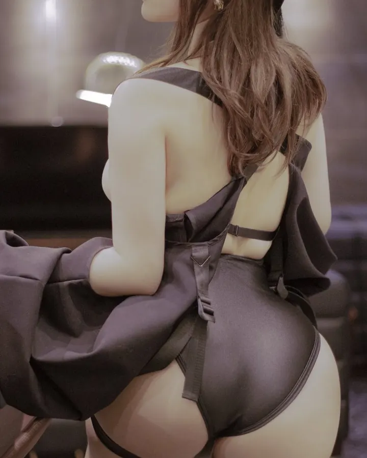 Femme vue de dos, robe noire nouée dans le dos, cheveux roux longs, lumière chaude.
