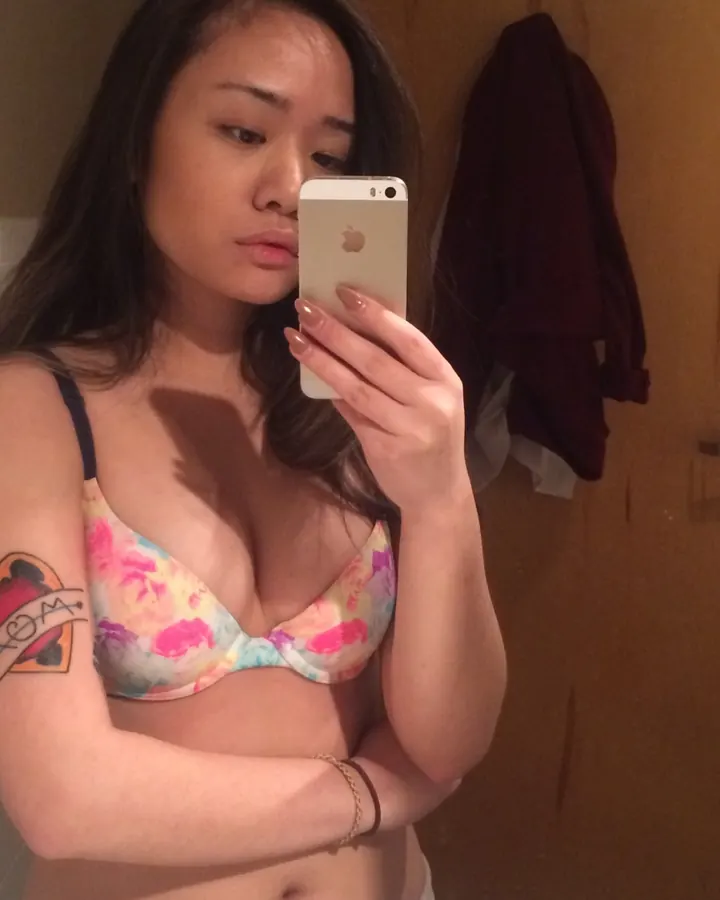 Jeune femme aux longs cheveux noirs en soutien-gorge fleuri, selfie miroir.