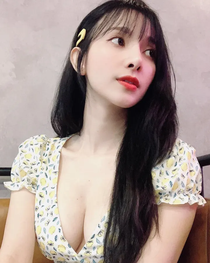 Jeune femme asiatique aux cheveux noirs, robe à fleurs jaunes, regard de côté.