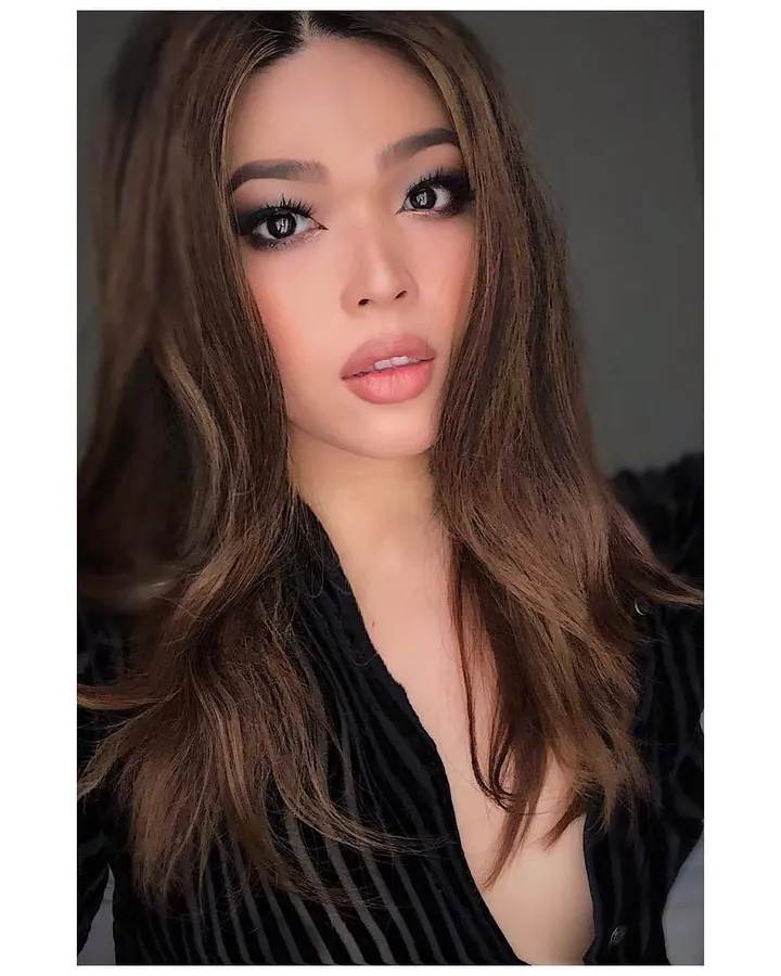 Jeune femme aux longs cheveux bruns, haut noir, regard direct vers l'objectif