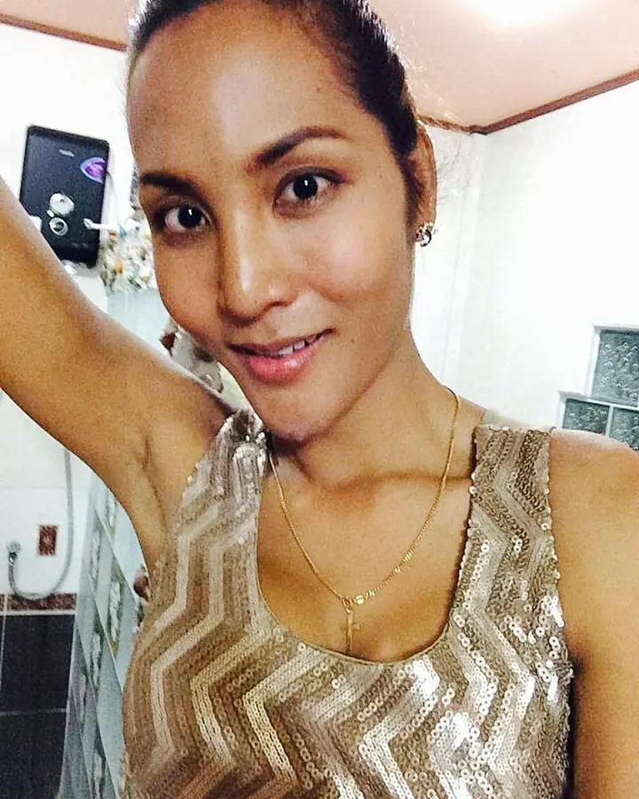 Femme brune au teint mat, souriante, en haut à sequins dorés.