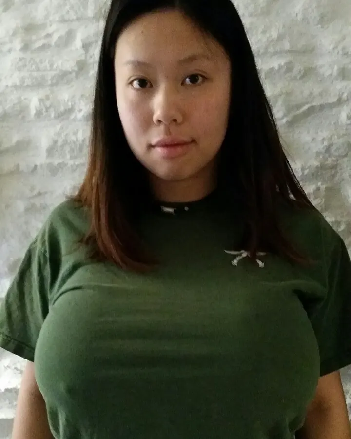 Femme asiatique en robe sombre, assise au sol, lumière naturelle et ombres marquées.