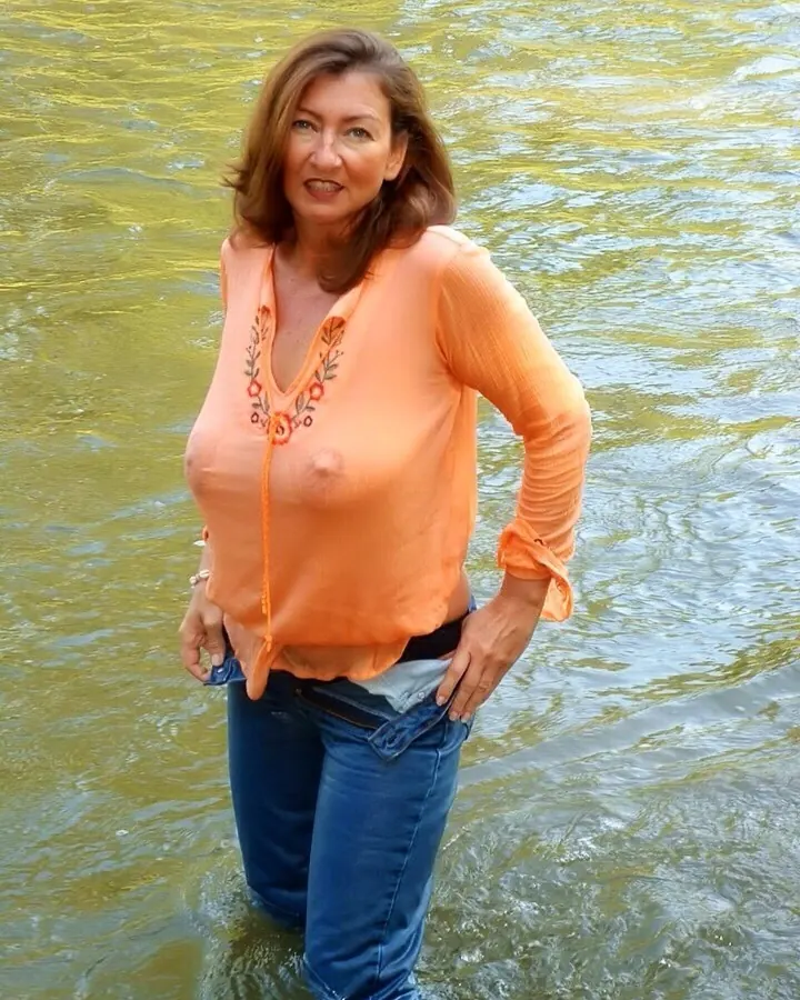 Femme blonde aux yeux clairs, sourire franc, dans une pièce éclairée.